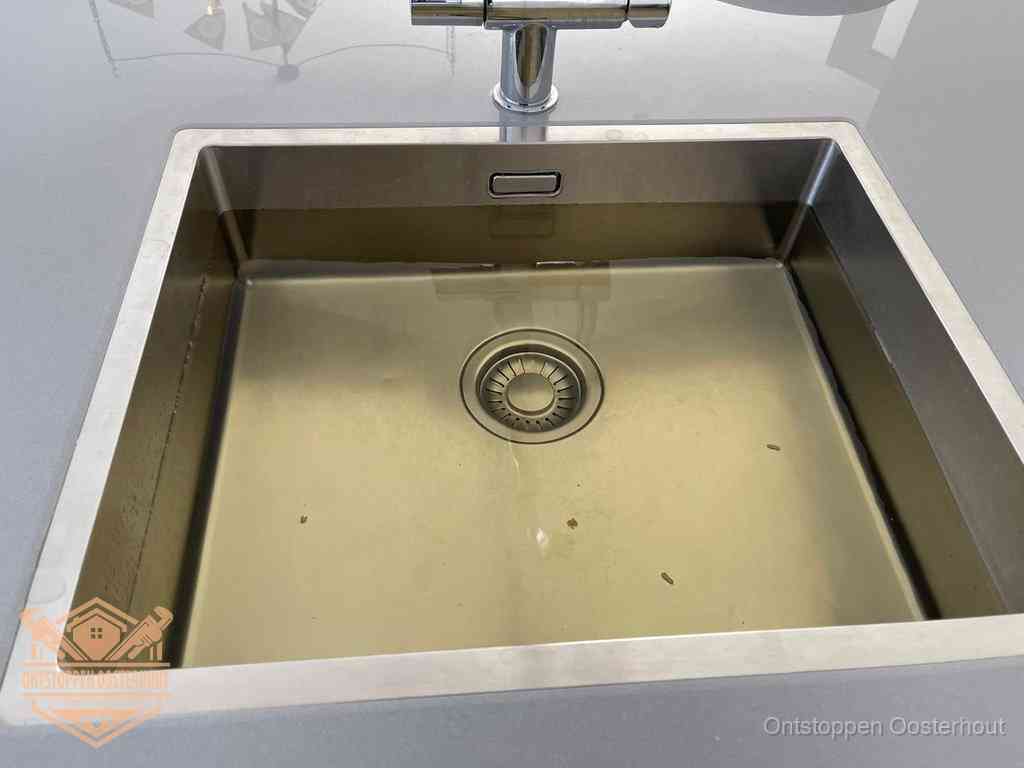 Stilstaand water in een rvs spoelbak dat niet wegloopt, een duidelijk signaal van een gootsteenverstopping in Oosterhout