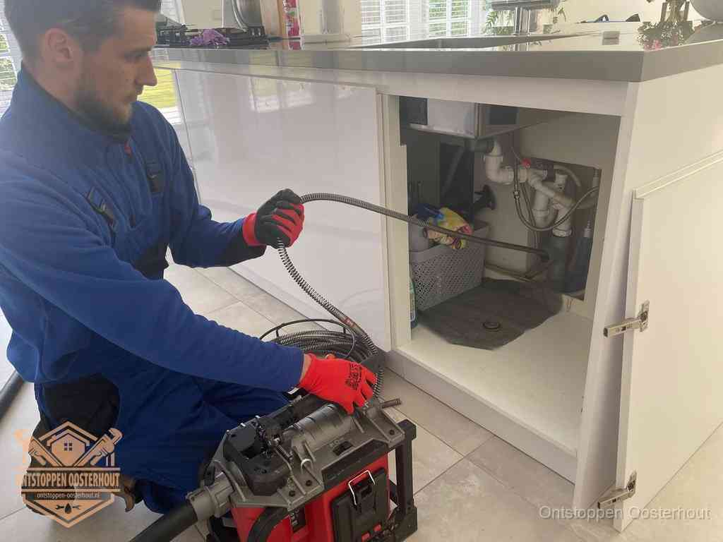 Een monteur reinigt de keukenafvoer grondig met een veermachine om terugkerende gootsteenverstoppingen te voorkomen in Oosterhout