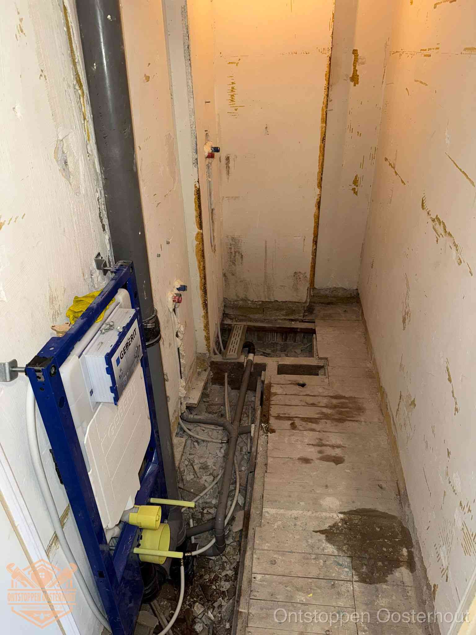 Een opgebroken toiletruimte tijdens renovatie met een Geberit inbouwreservoir en blootliggende oude afvoerleidingen, typisch voor oudere woningen in Oosterhout